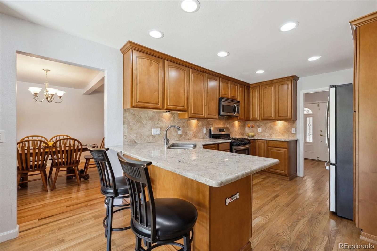 8403 Chase Drive Arvada, CO 80003 - Photo 6 of 39 a kitchen with granite countertop kitchen island wooden cabinets and stainless steel appliances