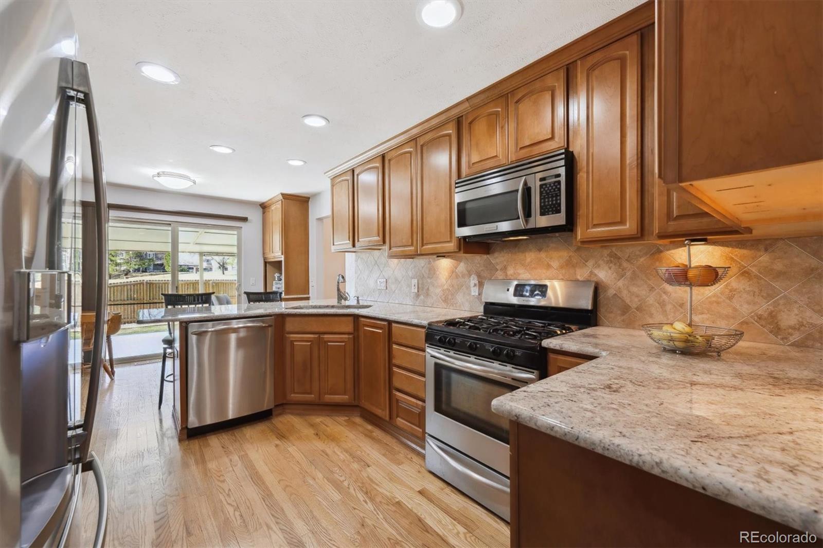 8403 Chase Drive Arvada, CO 80003 - Photo 7 of 39 a kitchen with granite countertop wooden cabinets stainless steel appliances and a sink