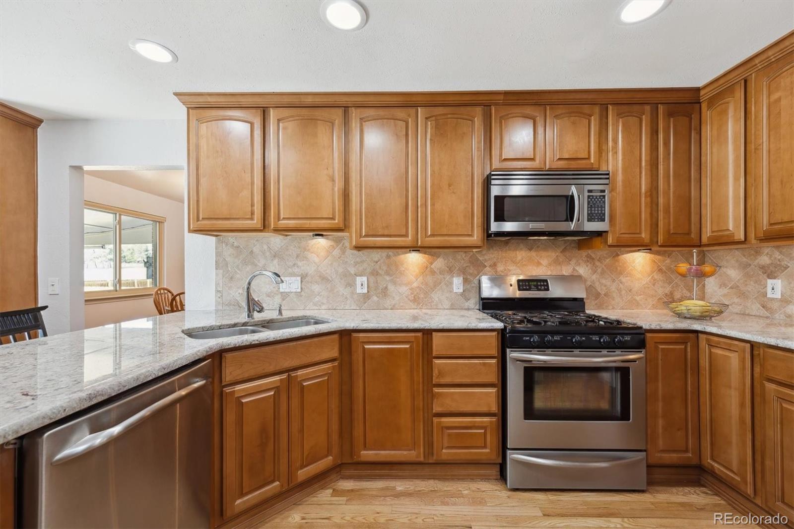 8403 Chase Drive Arvada, CO 80003 - Photo 8 of 39 a kitchen with granite countertop wooden cabinets and stainless steel appliances