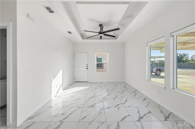 an empty room with windows and fan