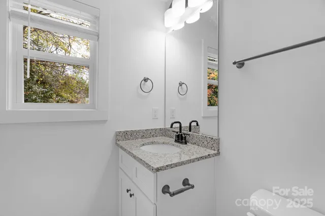 a bathroom with a granite countertop sink a mirror and shower