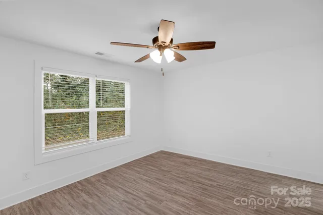 an empty room with a window and a fan