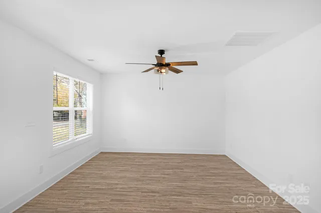 a view of empty room with wooden floor and fan