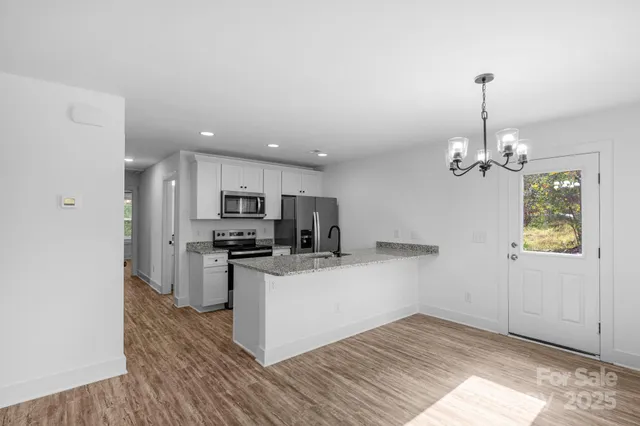 a kitchen with stainless steel appliances kitchen island granite countertop a refrigerator a stove a microwave oven a sink with wooden floor and cabinets
