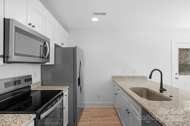 a kitchen with granite countertop a stove and a microwave