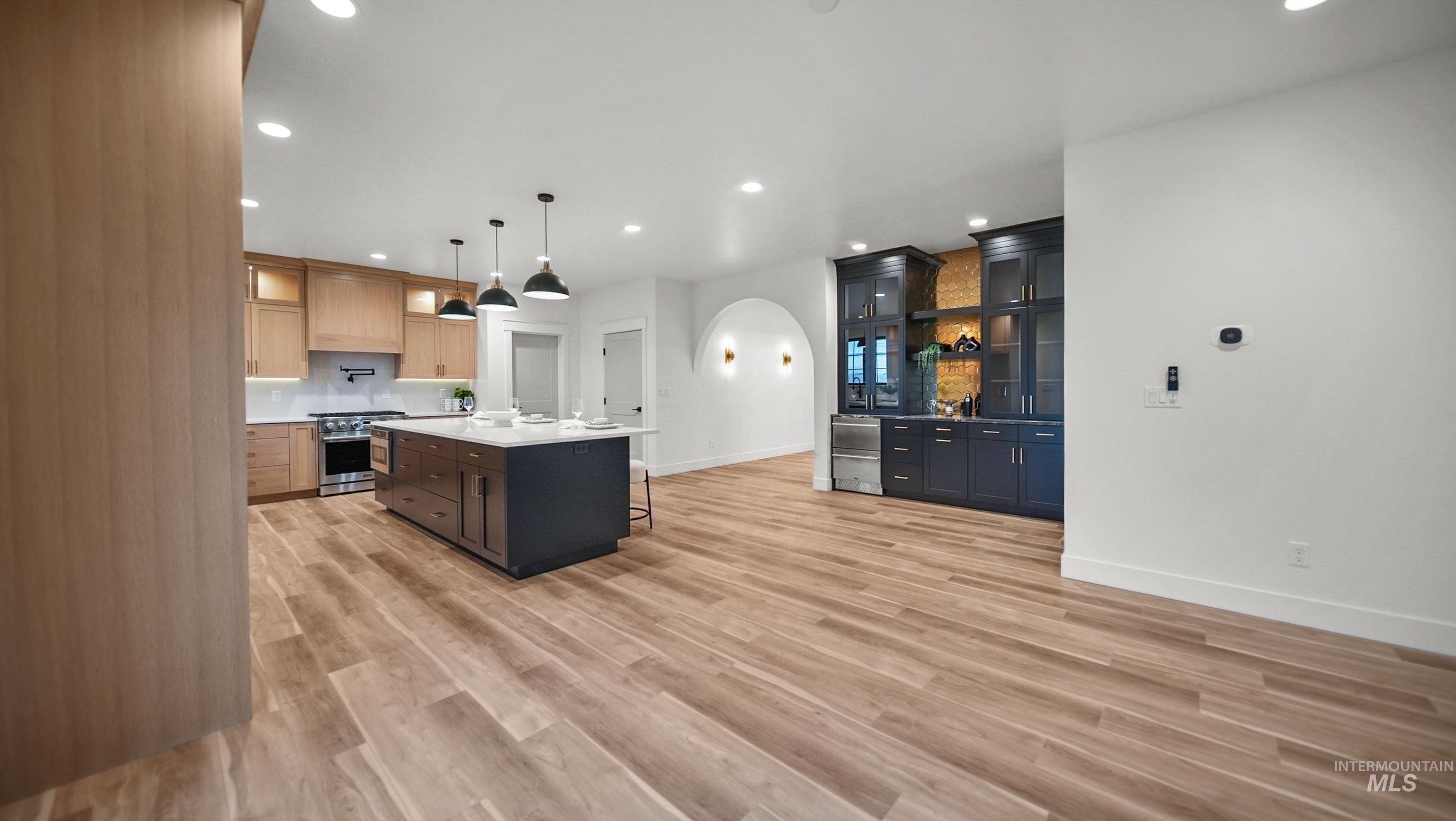 696 Full Moon Way Twin Falls, ID 83301 - Photo 12 of 48 Kitchen featuring a kitchen bar, arched walkways, recessed lighting, glass insert cabinets, and a kitchen island