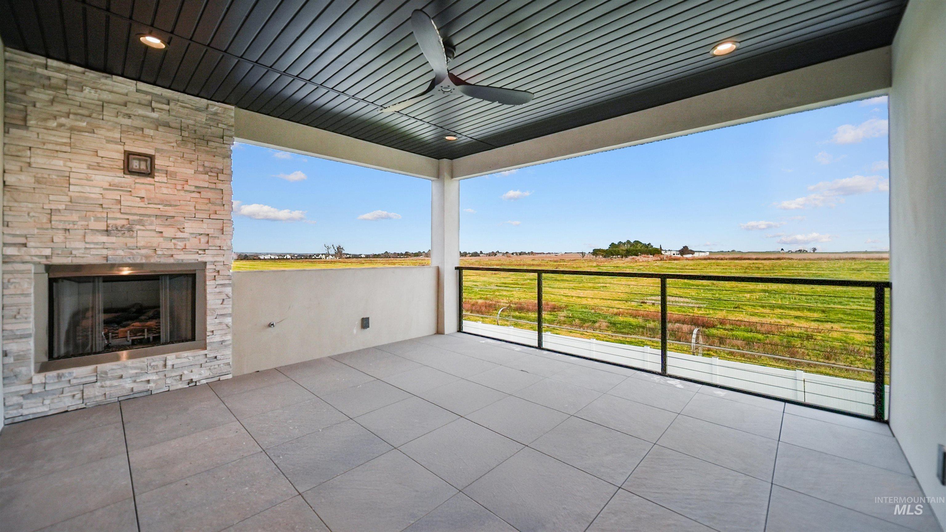 696 Full Moon Way Twin Falls, ID 83301 - Photo 18 of 48 View of patio / terrace with an outdoor stone fireplace, a ceiling fan, and a view of countryside