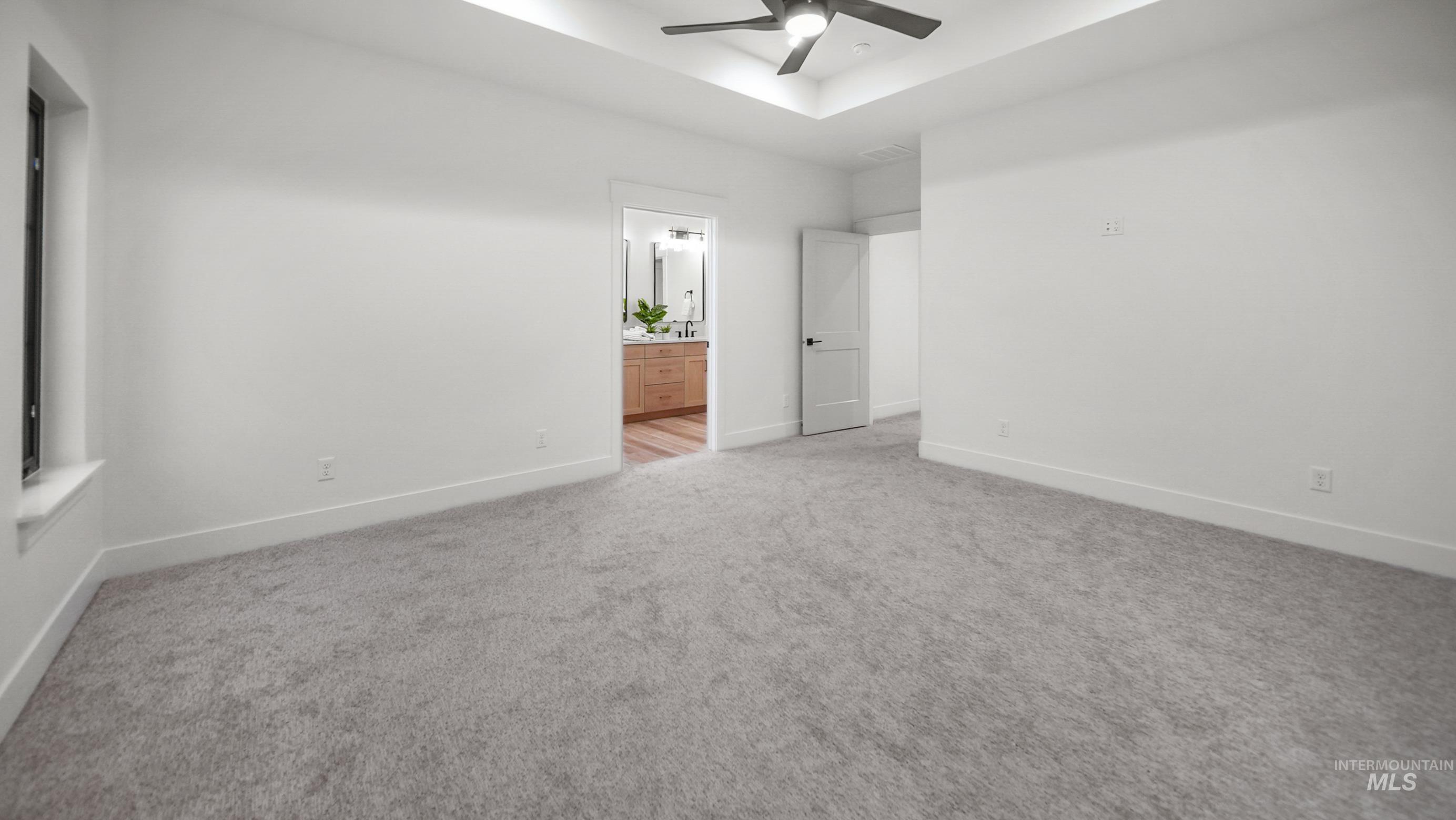 696 Full Moon Way Twin Falls, ID 83301 - Photo 23 of 48 Unfurnished bedroom featuring light colored carpet, ceiling fan, ensuite bathroom, and a tray ceiling