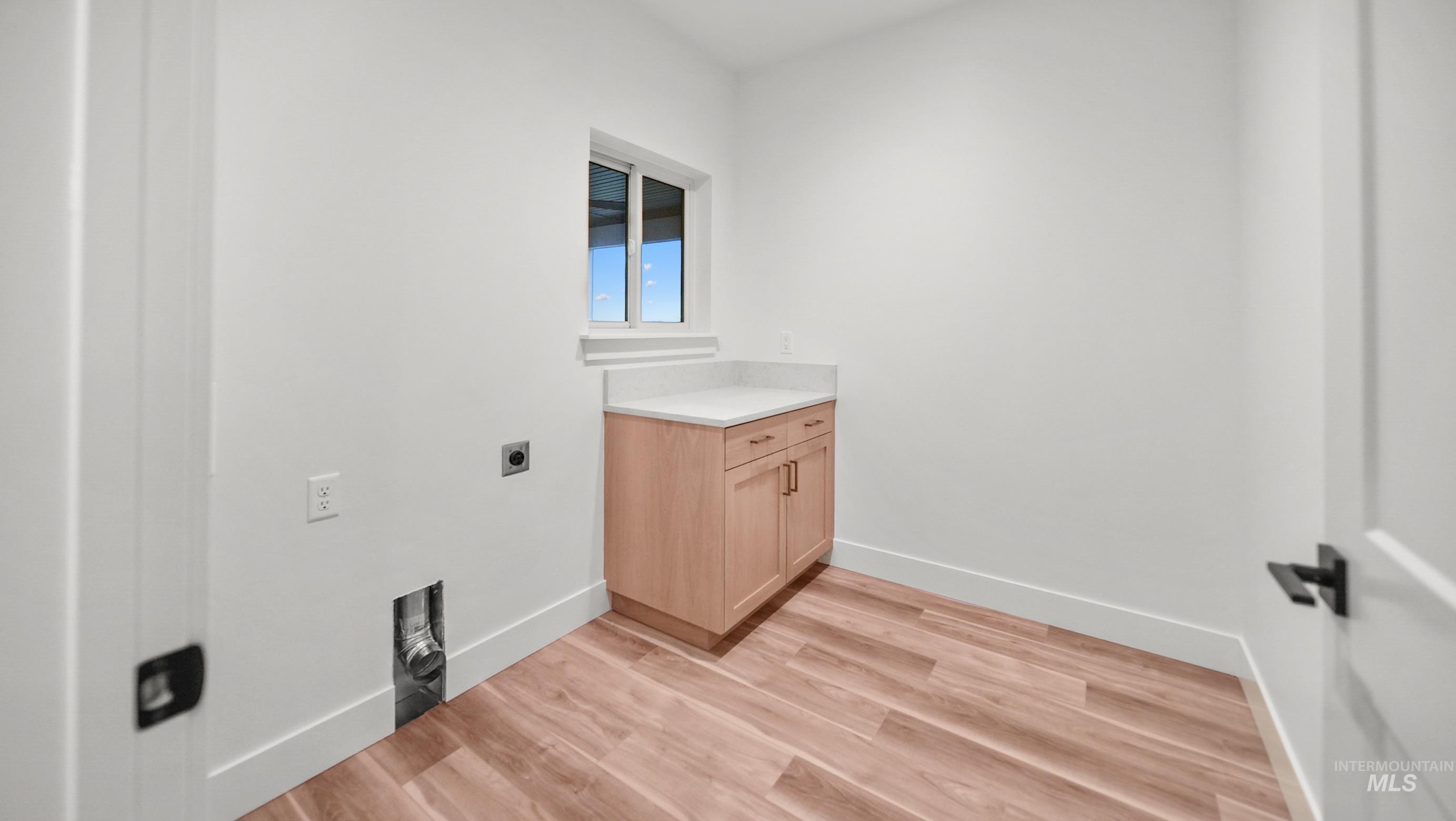 696 Full Moon Way Twin Falls, ID 83301 - Photo 32 of 48 Washroom with electric dryer hookup, light wood-style flooring, and cabinet space