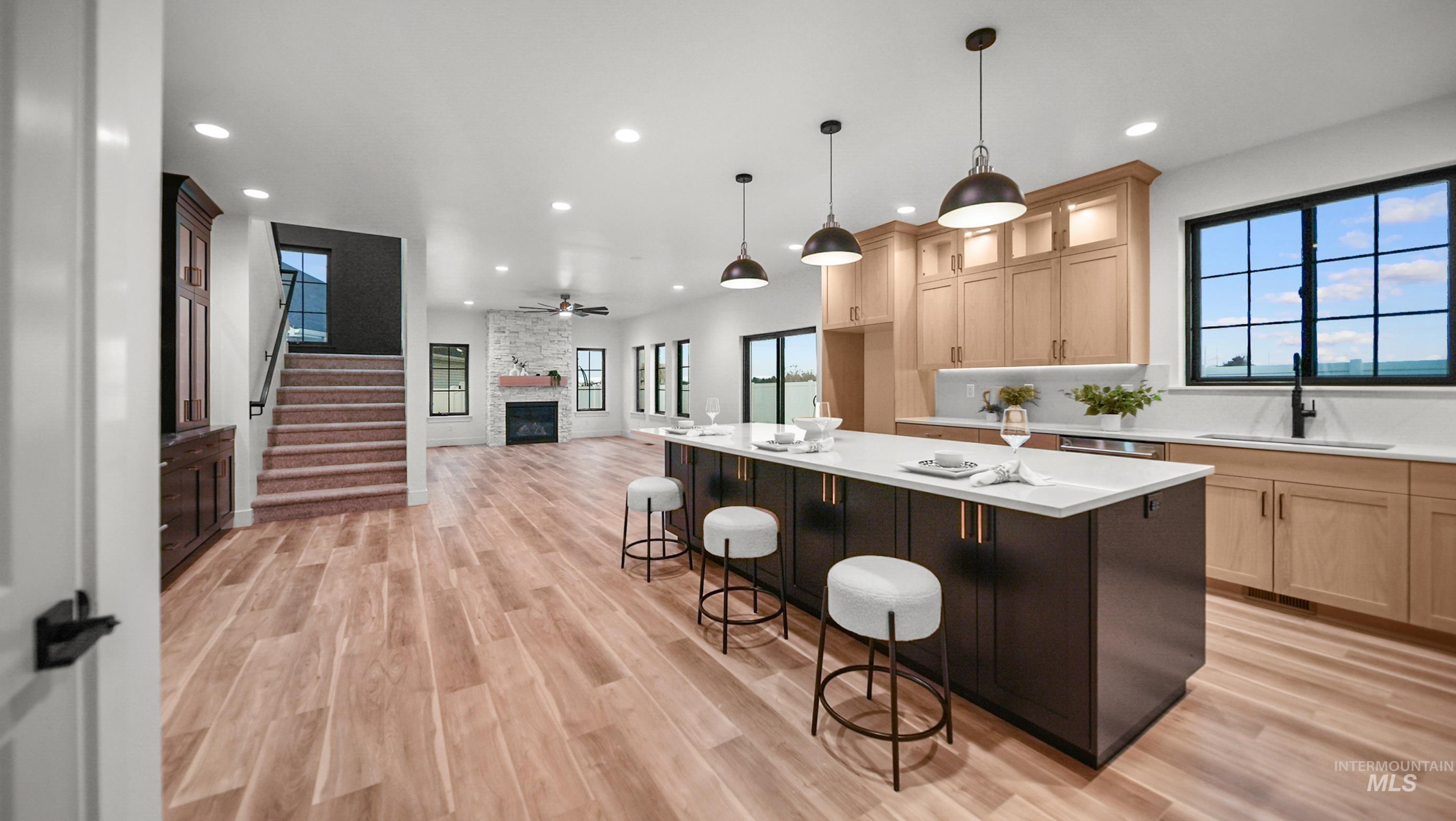 696 Full Moon Way Twin Falls, ID 83301 - Photo 47 of 48 Kitchen featuring light brown cabinetry, a stone fireplace, a breakfast bar, open floor plan, and a ceiling fan