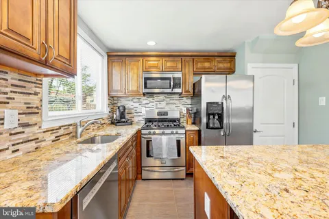 a kitchen with stainless steel appliances granite countertop a sink a stove and a refrigerator