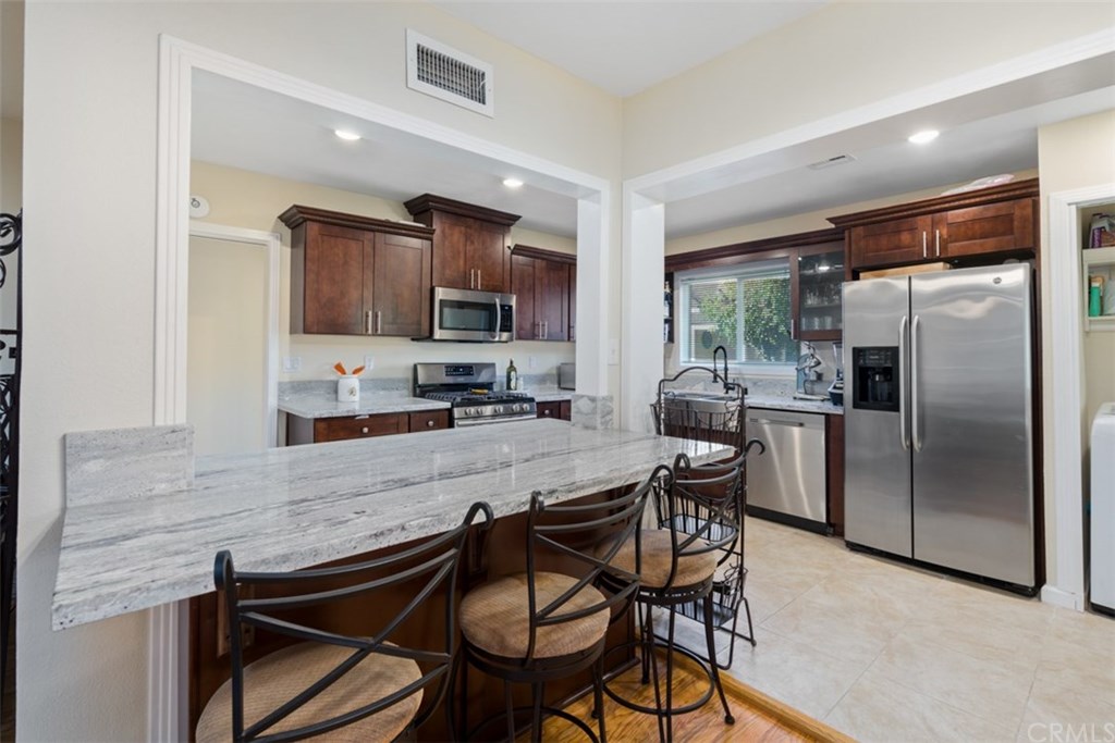 7955 Brookpark Road Downey, CA 90240 - Photo 9 of 27 a kitchen with stainless steel appliances granite countertop a stove top oven a refrigerator a sink and chairs