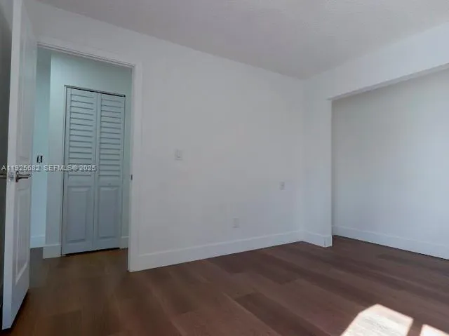 an empty room with wooden floor and closet