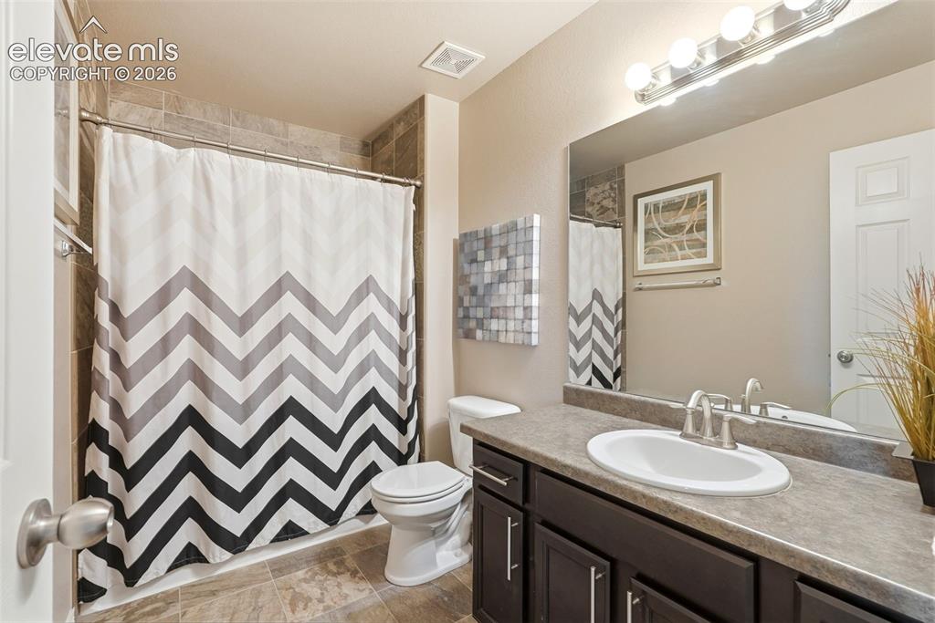 2264 Reed Grass Way Colorado Springs, CO 80915 - Photo 29 of 50 a bathroom with a granite countertop sink a toilet and a mirror
