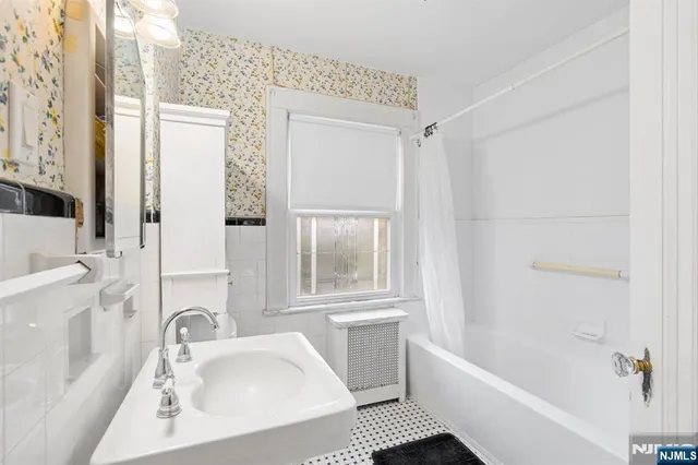 a white bath tub sitting next to a white sink and a window
