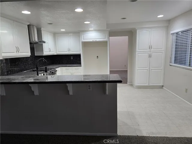 a kitchen with granite countertop white cabinets and stainless steel appliances