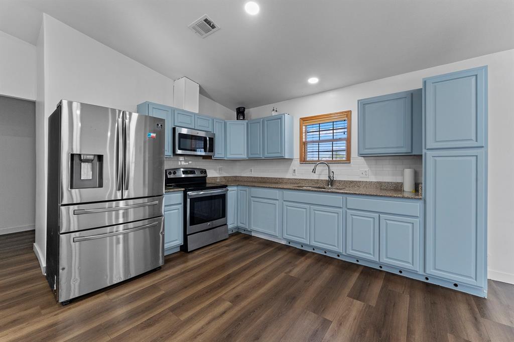1222 Anglin Way Terrell, TX 75161 - Photo 13 of 26 Bright, open kitchen featuring abundant cabinet and counter space, stainless-steel appliances, recessed lighting, and wood-look flooring.