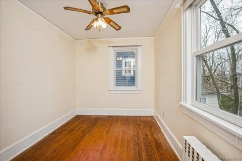 a view of an empty room with a window and wooden floor