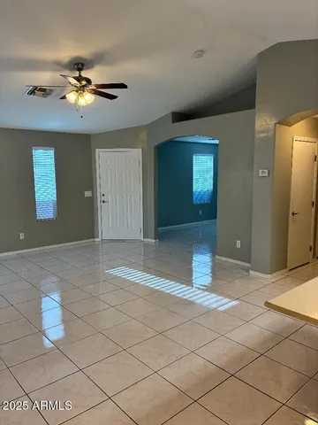 a view of a livingroom with a chandelier fan and kitchen area