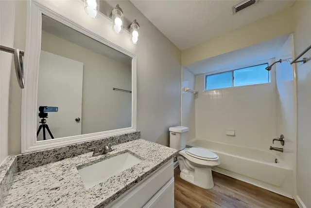 a bathroom with a granite countertop sink a toilet and shower