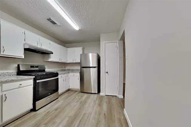 a kitchen with stainless steel appliances granite countertop a stove a sink and a refrigerator