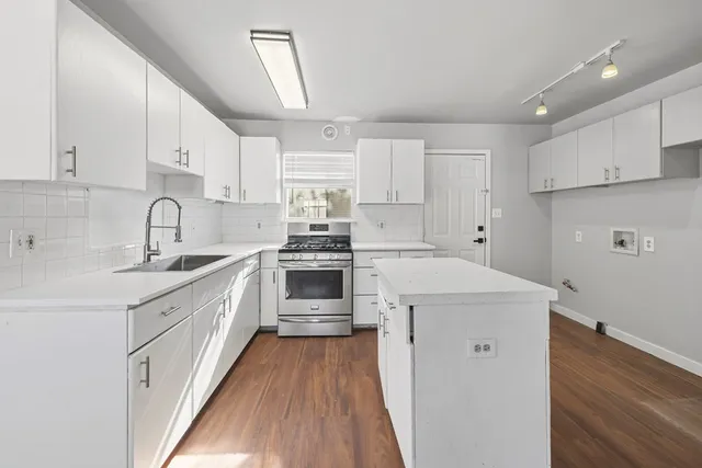 a kitchen with a sink a stove a refrigerator and white cabinets
