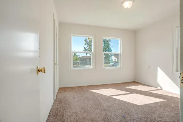 a view of an empty room with closet and a window
