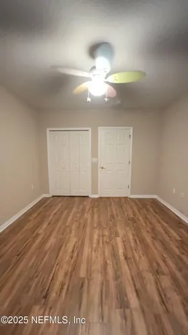 an empty room with wooden floor fan and window