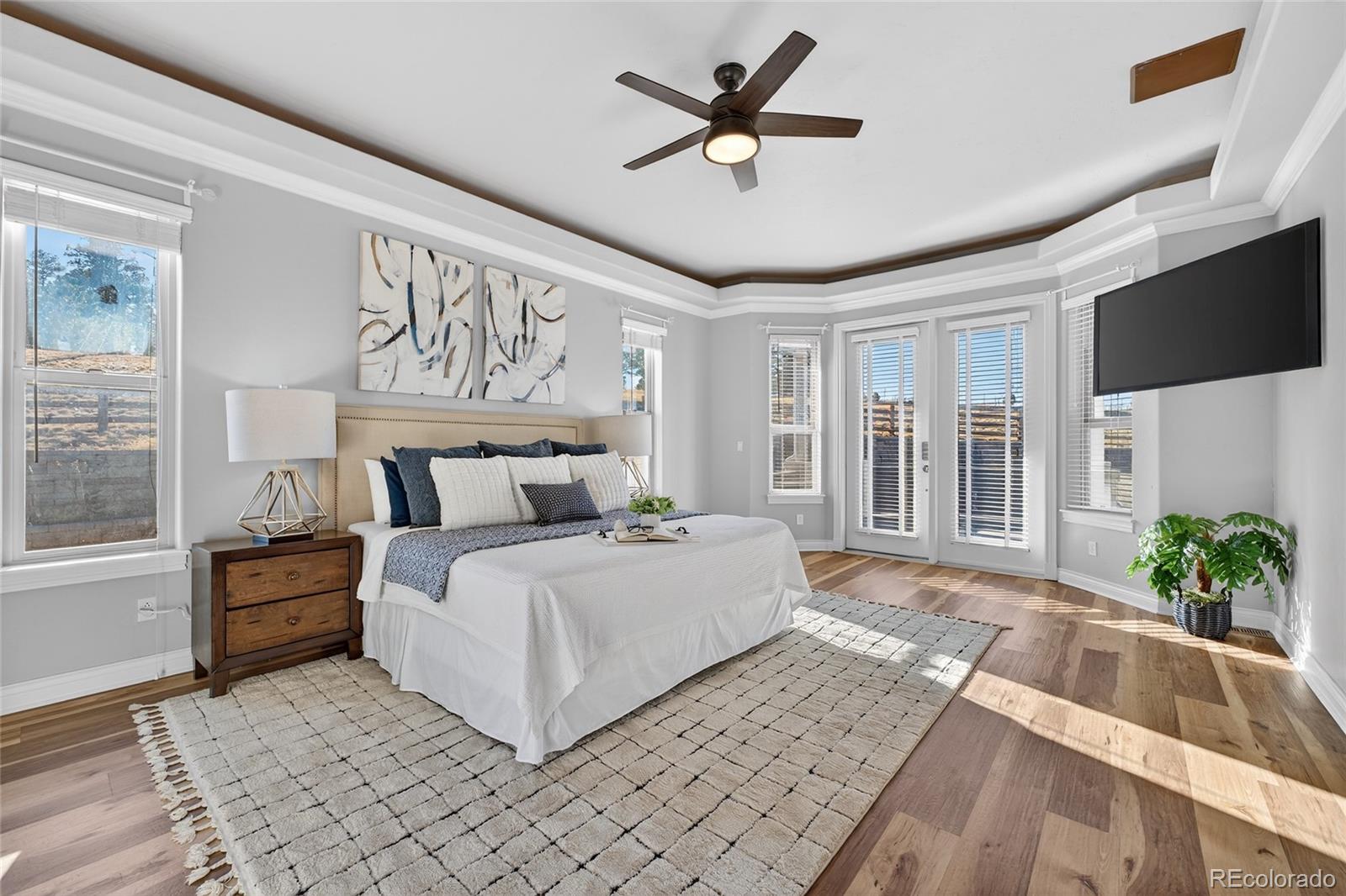 575 Howling Circle Elizabeth, CO 80107 - Photo 12 of 48 a spacious bedroom with a large bed a chandelier and windows