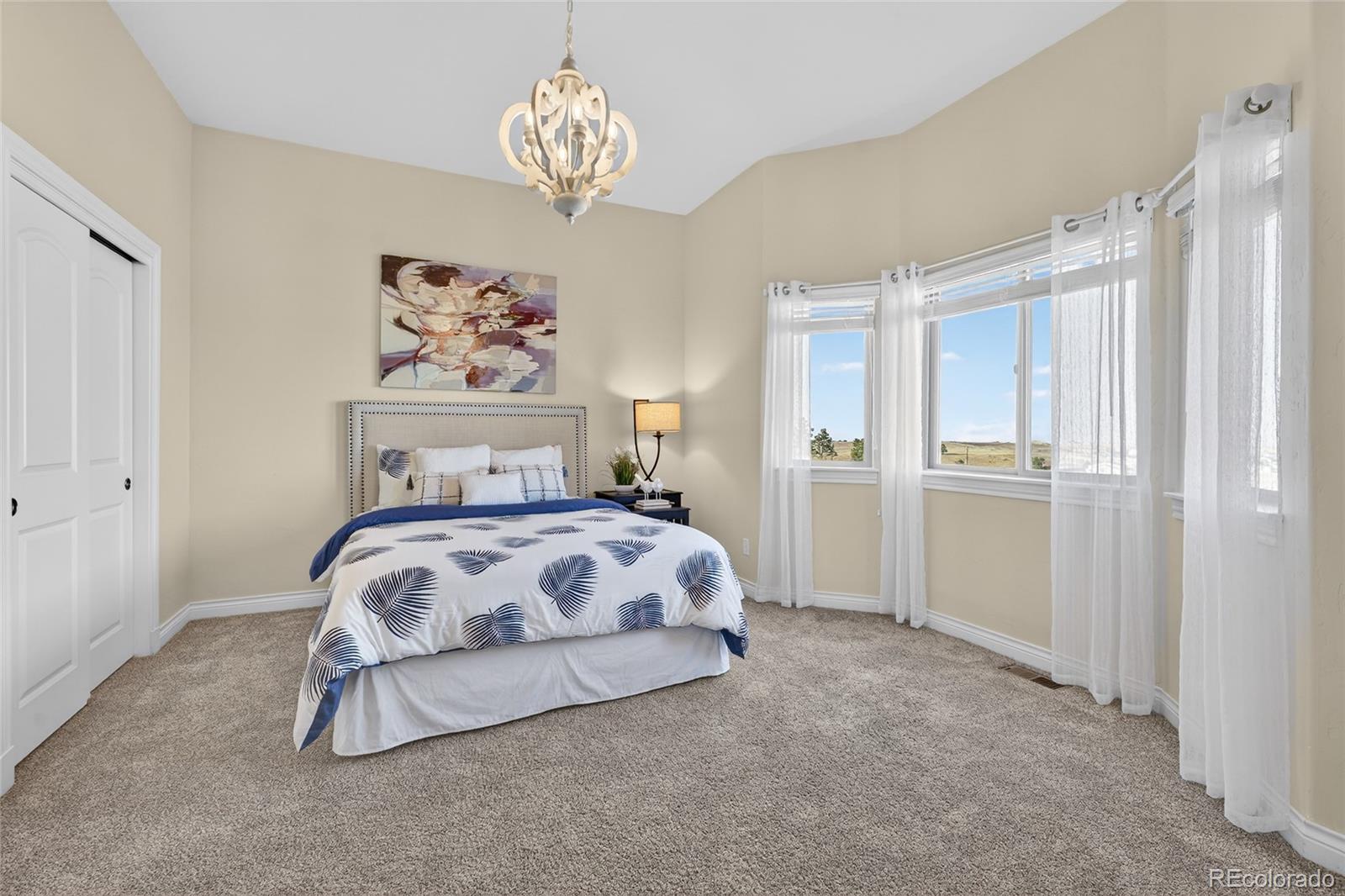 575 Howling Circle Elizabeth, CO 80107 - Photo 29 of 48 a bedroom with a bed and a chandelier