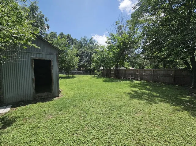 a view of a backyard with large trees and wooden fence