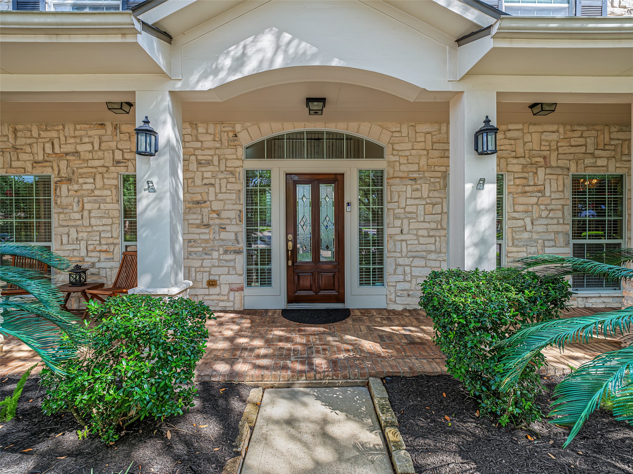 2210 Fox Path Katy, TX 77494 - Photo 4 of 47 Boasting exceptional curb appeal with its beautiful stone-and-brick facade, a classic front porch framed by mature trees, and an inviting walkway, this residence welcomes you into a spacious and light-filled layout designed for both effortless entertaining and comfortable family living.