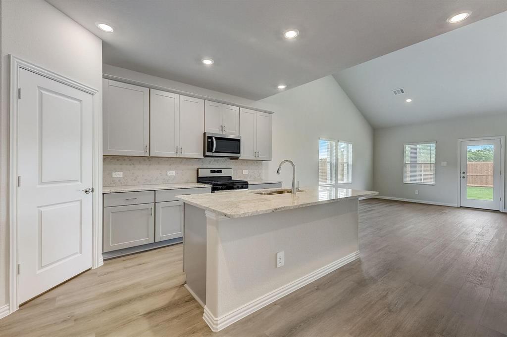 1405 Winters Way McKinney, TX 75071 - Photo 2 of 32 Kitchen featuring tasteful backsplash, sink, a kitchen island with sink, stainless steel appliances, and light wood-type flooring