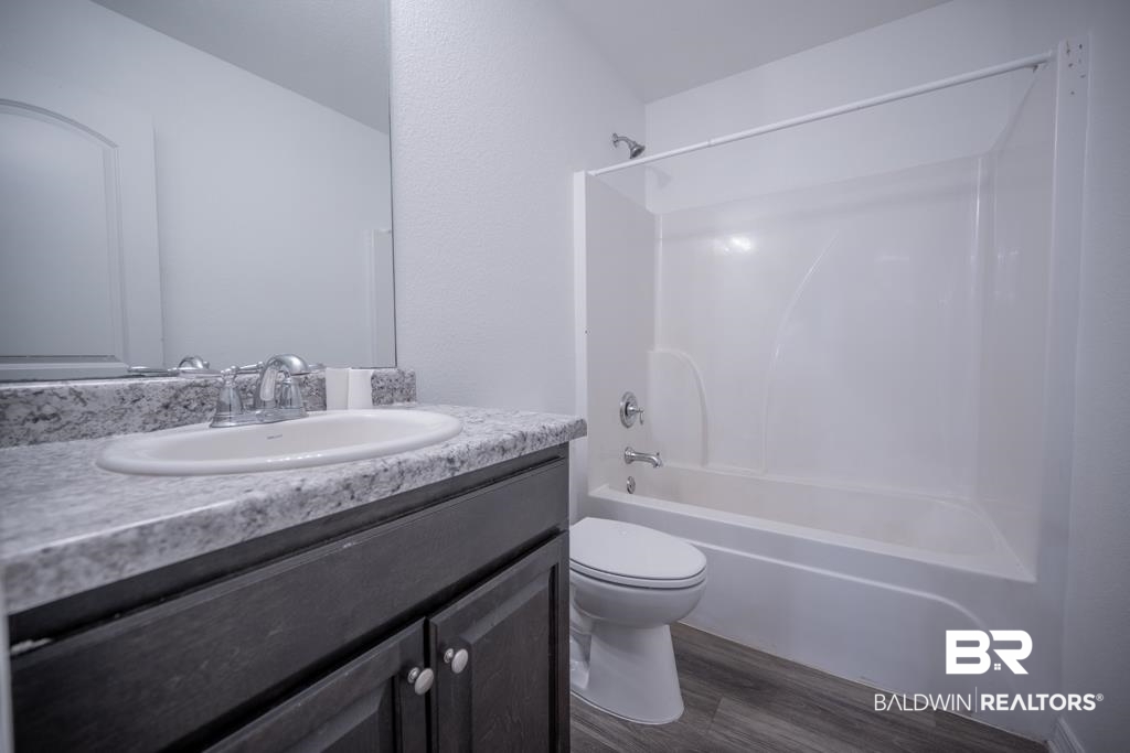 15874 Carver Road, Unit C Foley, AL 36535 - Photo 16 of 18 Full bathroom featuring bathing tub / shower combination, vanity, hardwood / wood-style floors, and toilet