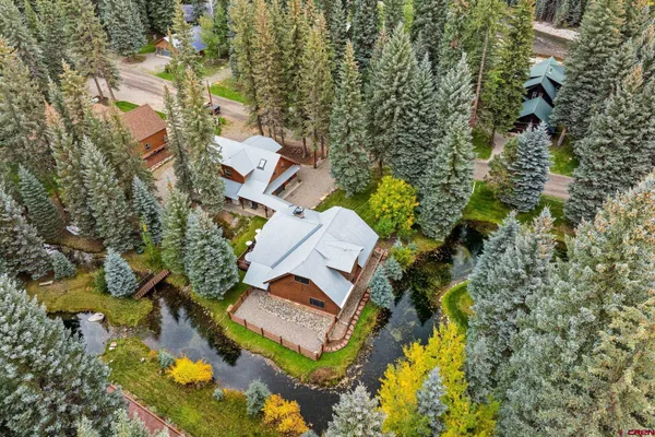 an aerial view of residential house with outdoor space and trees all around