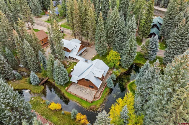 an aerial view of residential house with outdoor space and trees all around