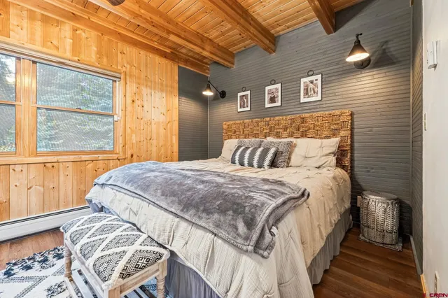a bedroom with a bed next to a window with wooden floor