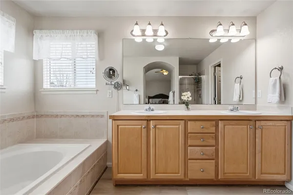 a spacious bathroom with a granite countertop sink a large mirror and a bathtub with view of bathroom