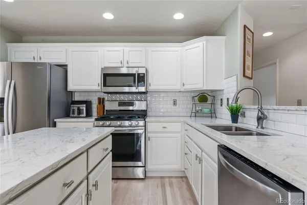 a kitchen with kitchen island granite countertop a sink stainless steel appliances and white cabinets