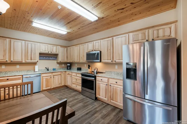 a kitchen with granite countertop stainless steel appliances a refrigerator a stove top oven a sink and cabinets