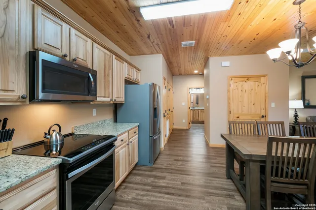 a kitchen with stainless steel appliances granite countertop a sink a stove and a wooden cabinets