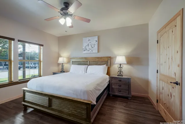 a bedroom with a bed and a large window with wooden floor