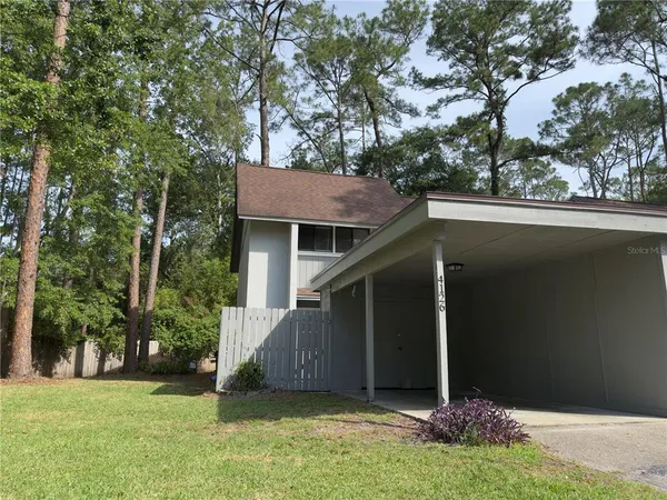 a view of a wooden house with a big yard and large trees