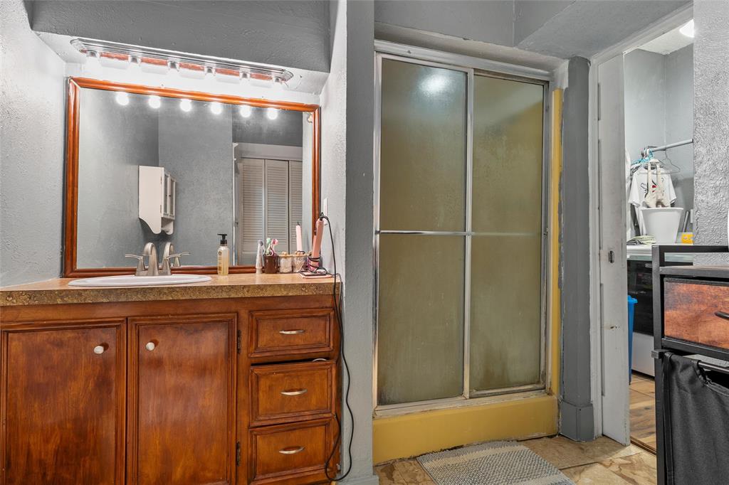 306 South Cleveland Meridian, TX 76665 - Photo 12 of 26 a bathroom with a granite countertop sink a mirror and a shower