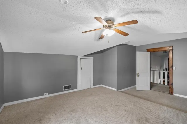 a view of a room with a ceiling fan and carpet