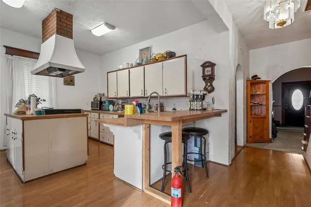 a kitchen with kitchen island granite countertop a sink a stove cabinets and wooden floor