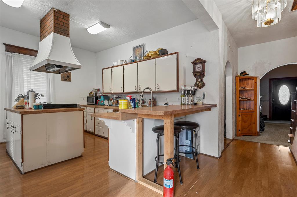 306 South Cleveland Meridian, TX 76665 - Photo 7 of 26 a kitchen with kitchen island granite countertop a sink a stove cabinets and wooden floor