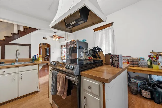 a view of a kitchen with kitchen island a sink a stove and wooden floor