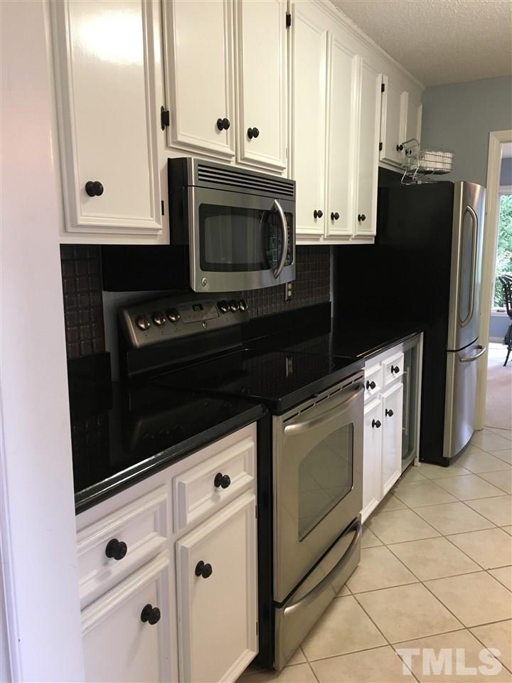 2850 Rue Sans Famille Raleigh, NC 27607 - Photo 9 of 24 a kitchen with stainless steel appliances white cabinets and a refrigerator