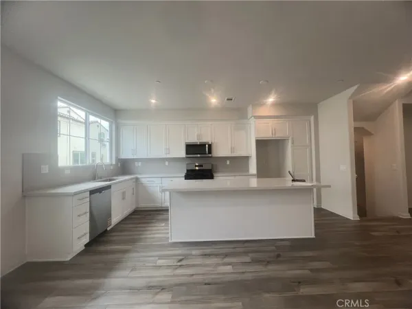 a large white kitchen with kitchen island a sink a stove a refrigerator and white cabinets